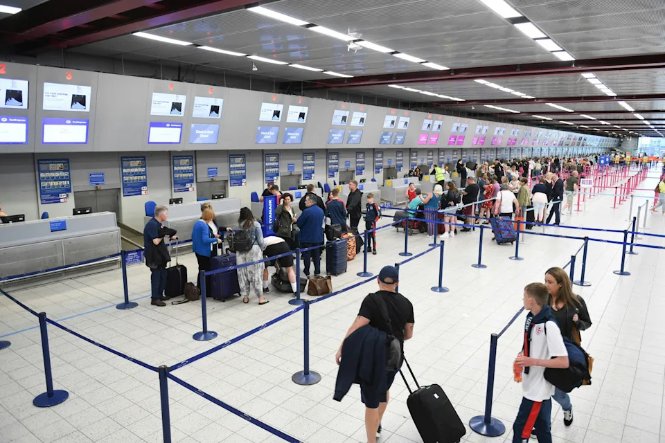 Passengers waiting in line at airport check-in counters with luggage