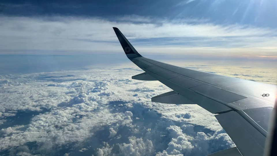 Airplane wing flying above the clouds during daylight