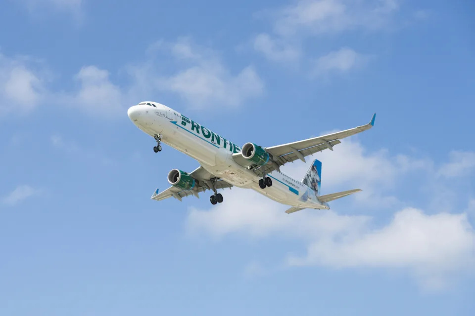 Frontier Airlines plane in the sky with landing gear down