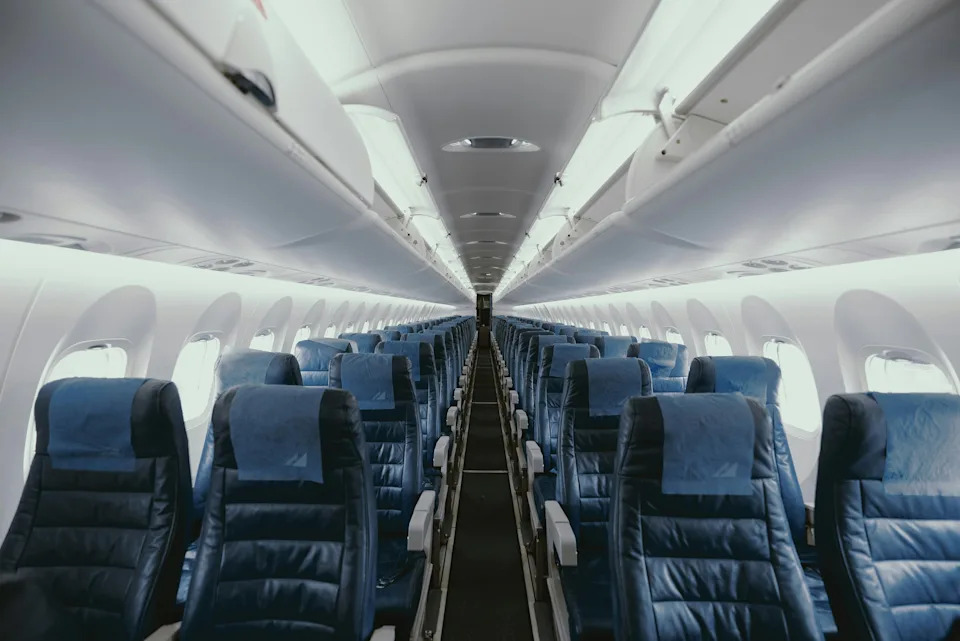 Empty economy class airplane cabin with blue seats and white lighting